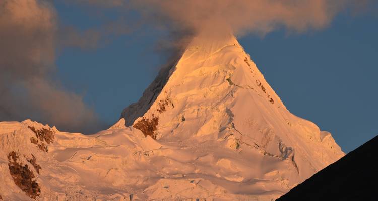 Snowy mountain peak glowing in the sunset.