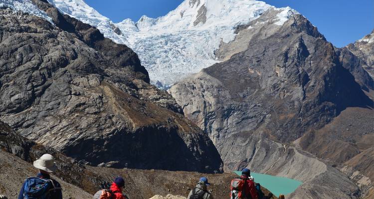 Hikers overlooking a glacial valley with a bright blue lake.