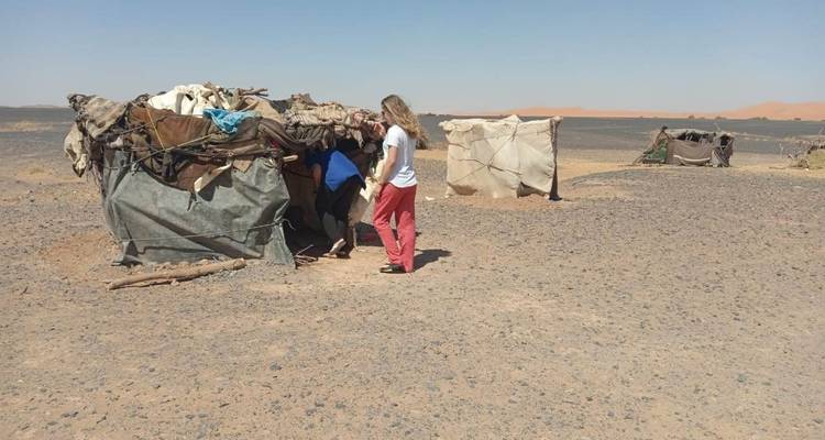 People visiting makeshift nomadic tents in the desert.