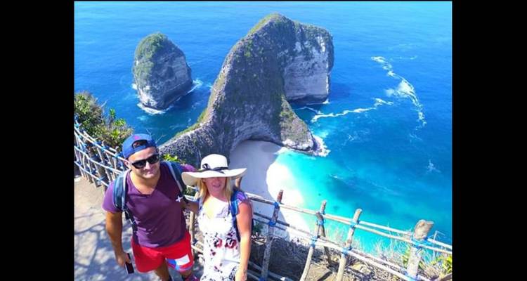 Touristen, die vor einer Kulisse aus atemberaubenden Küstenfelsen und blauem Wasser posieren.