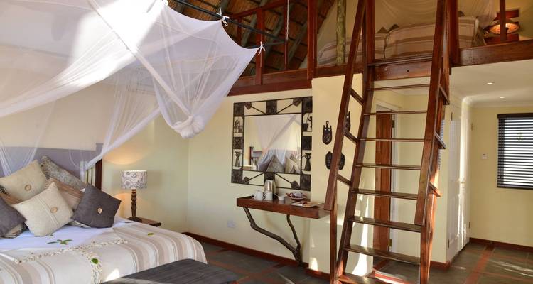 Interior of a cozy room with loft and mosquito net.