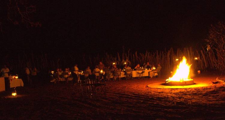 Nighttime outdoor dining with a bonfire.