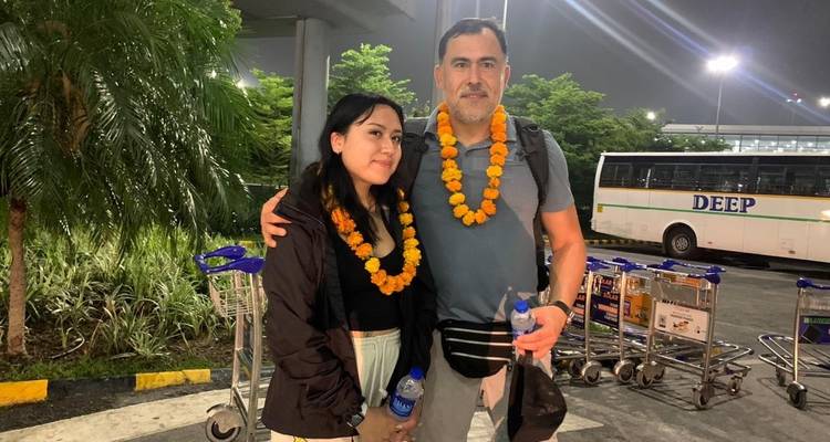 A couple with marigold garlands at an airport.