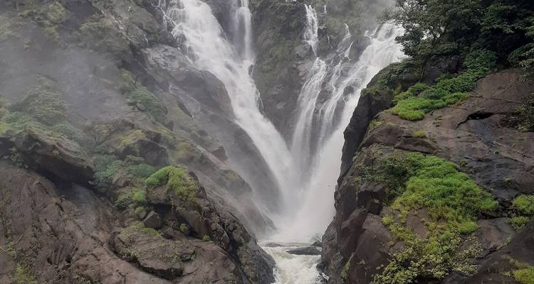 Nahaufnahme eines kraftvollen Wasserfalls, der über Felsen hinabstürzt.