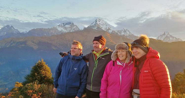 Vier mensen poseren met bergen op de achtergrond.