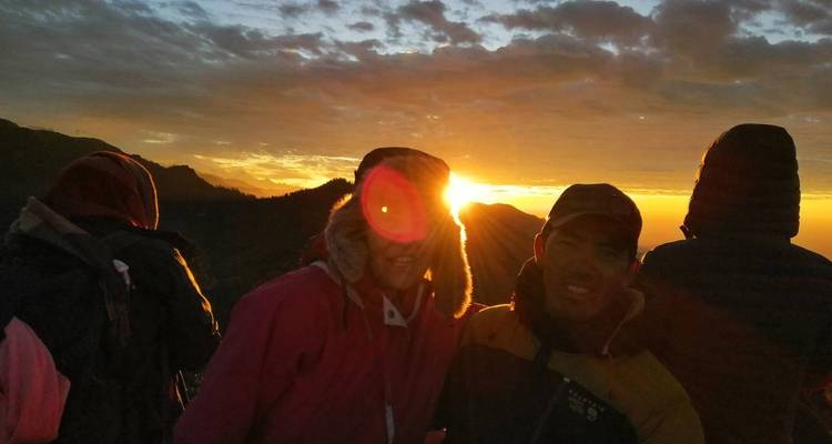 Groep mensen die een zonsondergang boven de bergen bekijkt.