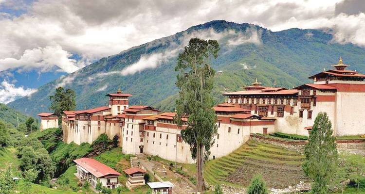 Un grand complexe monastique sur une colline avec des terrasses et des arbres.