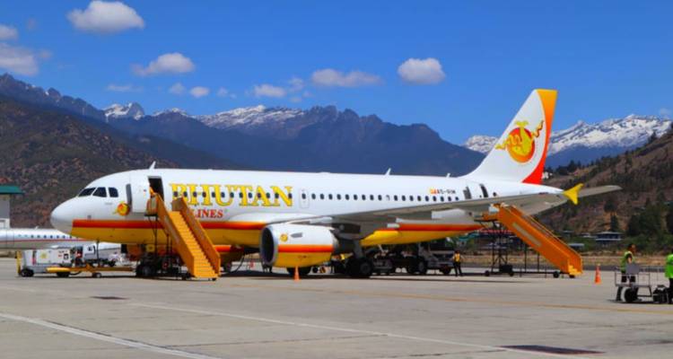 Un avion garé sur une piste avec des montagnes en arrière-plan.