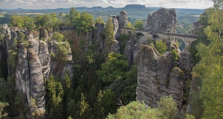 Formations rocheuses avec un environnement boisé et un pont piétonnier.