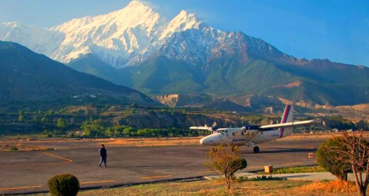 Flugzeug auf einer Start- und Landebahn mit Bergen im Hintergrund.