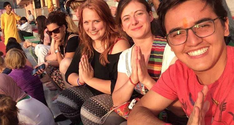 Groep mensen die samen zitten, glimlachen en elkaar begroeten.