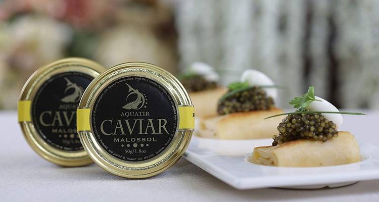 Chique presentatie van kaviaar in blikjes en kleine pannenkoekjes met garnering.