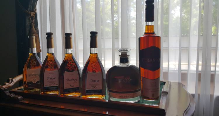 Dienblad met verschillende flessen sterkedrank naast een raam met gordijnen.