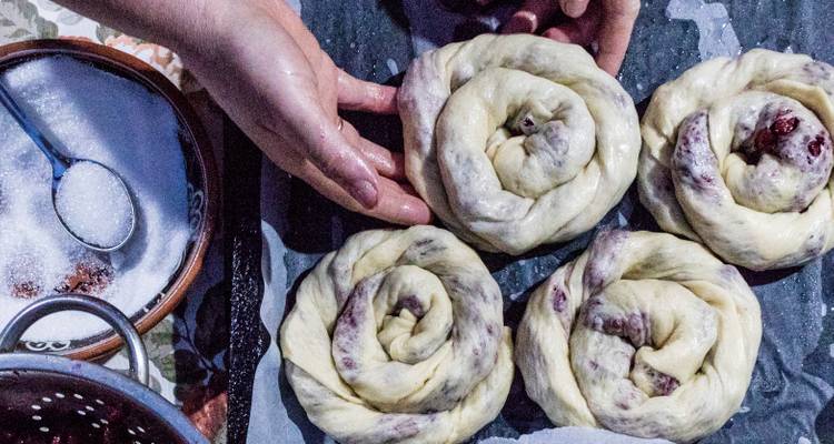Personne préparant des pâtes à pain crues sur une table.