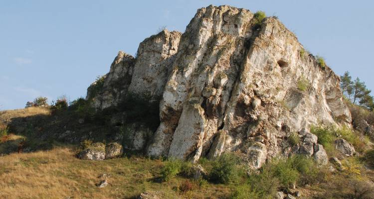 Falaise rocheuse entourée d'un terrain herbeux.