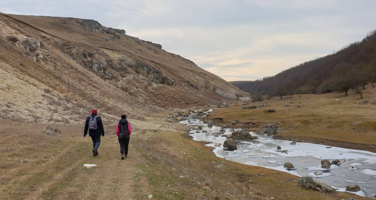 Deux personnes marchant le long d'un ruisseau dans une zone rurale.