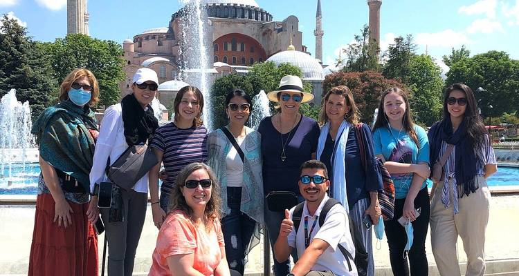 Des touristes posent devant une fontaine avec l'immense dôme de Sainte-Sophie en arrière-plan.