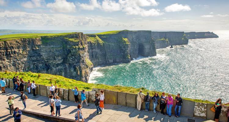 Les touristes se rassemblent le long des spectaculaires Falaises de Moher, qui s'élèvent majestueusement au-dessus de l'Atlantique avec les vagues qui s'écrasent en contrebas.