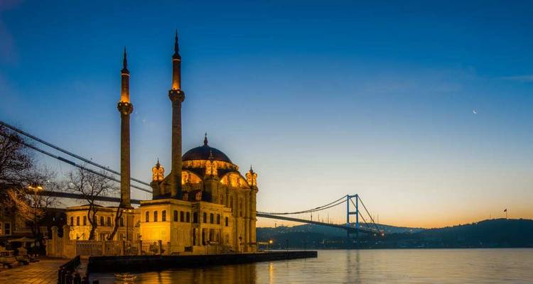 Moskee bij het water en brug tijdens zonsondergang.