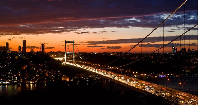 Hangbrug verlicht bij zonsondergang.