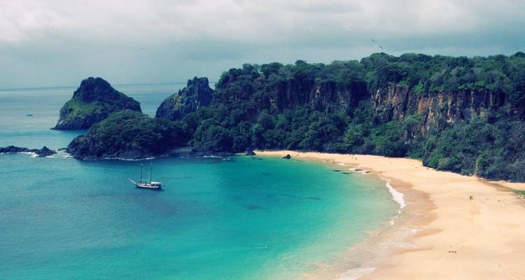 Hermosa playa con agua turquesa y un acantilado.