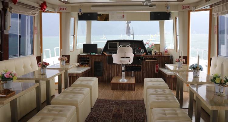 Interior of a boat with tables and chairs, overlooking the water.