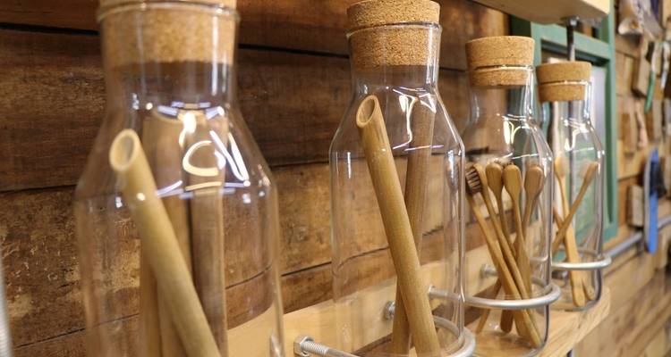 Bottles with cork stoppers and bamboo straws on a wooden shelf.