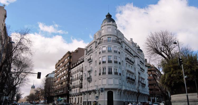 Elegant hoekgebouw in een stadsstraat met verkeerslichten en auto's.