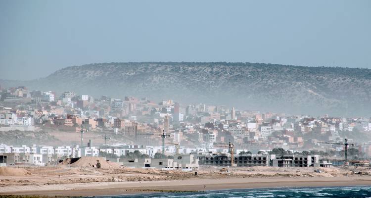Coastal cityscape with buildings and a hazy sky.