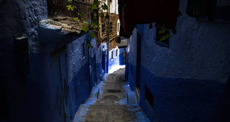 Narrow alley in a Moroccan town with blue painted walls.