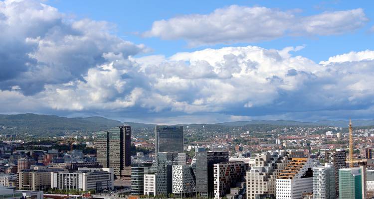 Skyline of a city with modern buildings and mountains in the background.