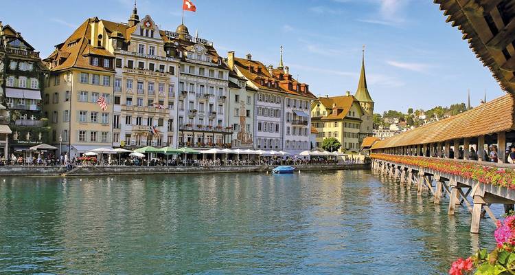 Front de mer historique de Lucerne avec ses façades colorées et le pont de la Chapelle bordé de fleurs enjambant la rivière Reuss.