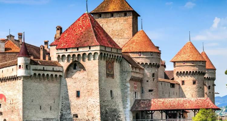 Middeleeuws Château de Chillon met rode pannendaken torens staat aan het meer tegen alpijnse blauwe lucht.