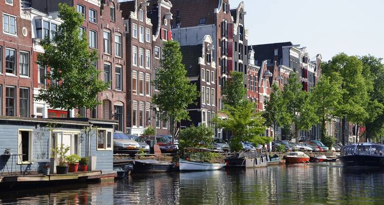 Scenic canal with traditional Dutch buildings and trees alongside.