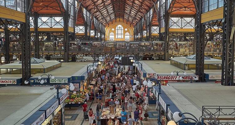Mercado cubierto bullicioso con gente y puestos.