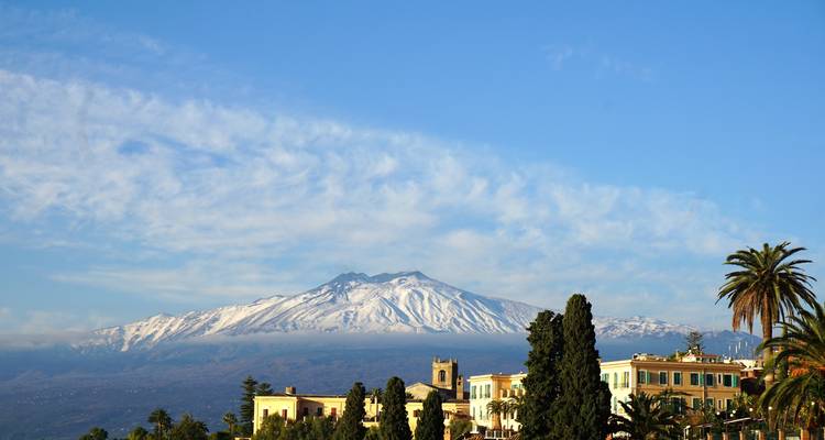 Mount Etna with snow-capped peak above a town.