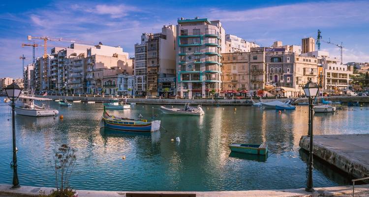 Paisaje urbano costero moderno con edificios coloridos y barcos.