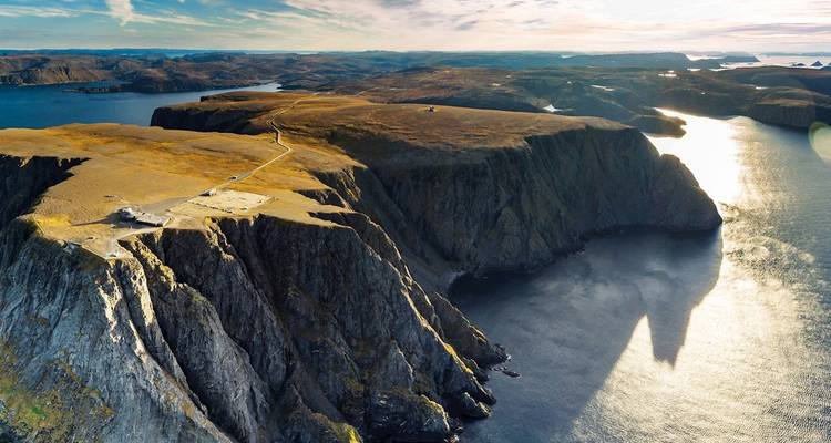 Vue aérienne de falaises côtières abruptes et d'un vaste océan au Cap Nord de la Norvège dans la lumière du soir tardif.