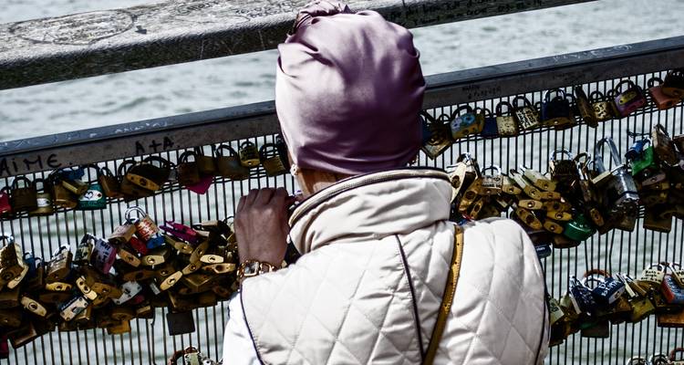 Person, die stehen bleibt, um Liebesschlösser auf einer Brücke zu betrachten.