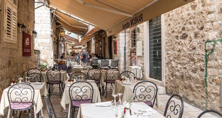Outdoor cafe in Dubrovnik's narrow cobblestone street.