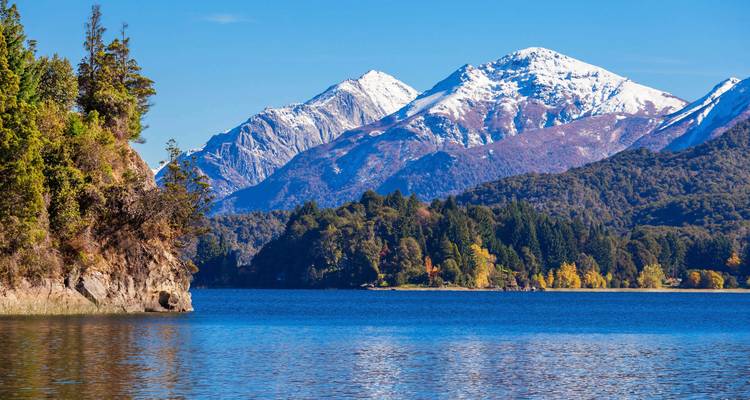 Schneebedeckte Berge mit einem See im Vordergrund.