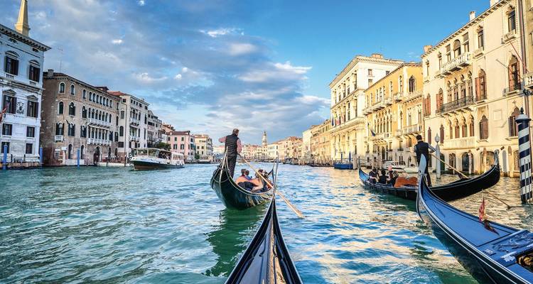 Gondoles naviguant sur les canaux de Venise sous un ciel bleu dégagé.