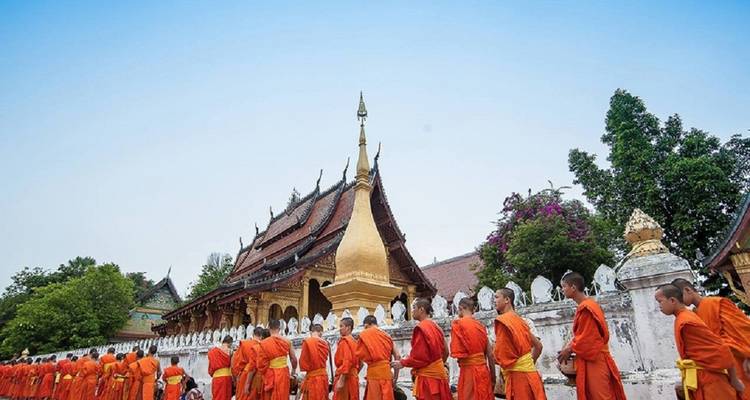 Procession de moines en robes orange près d'un temple.