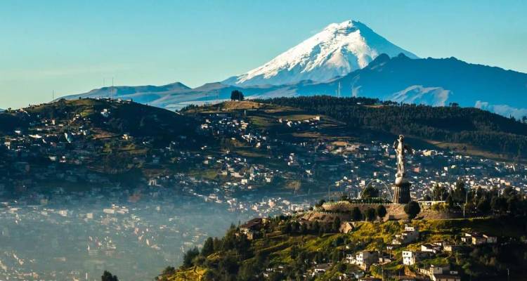 Le volcan Cotopaxi aux pics enneigés s'élève majestueusement au-dessus de l'étendue urbaine de Quito à l'aube.