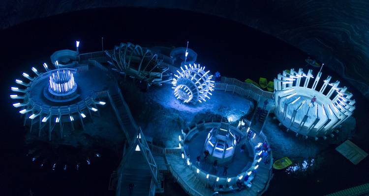 Verlichte futuristische houten platforms en reuzenrad-achtige constructies in de Turda-zoutmijn.