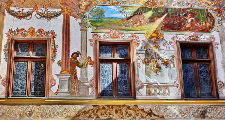 Kleurrijke barokke fresco's en sierlijke ramen op de gevel van een historisch Transsylvanisch gebouw.