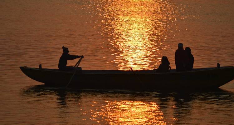 Eine Silhouette von Menschen in einem Boot bei Sonnenuntergang.