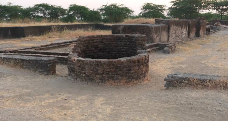 Antike Ruinen mit Steinstrukturen und Bäumen im Hintergrund.