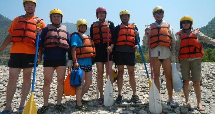 Group of people prepared for rafting with paddles.