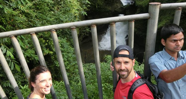 Tourists posing on a bridge with a waterfall in the background.